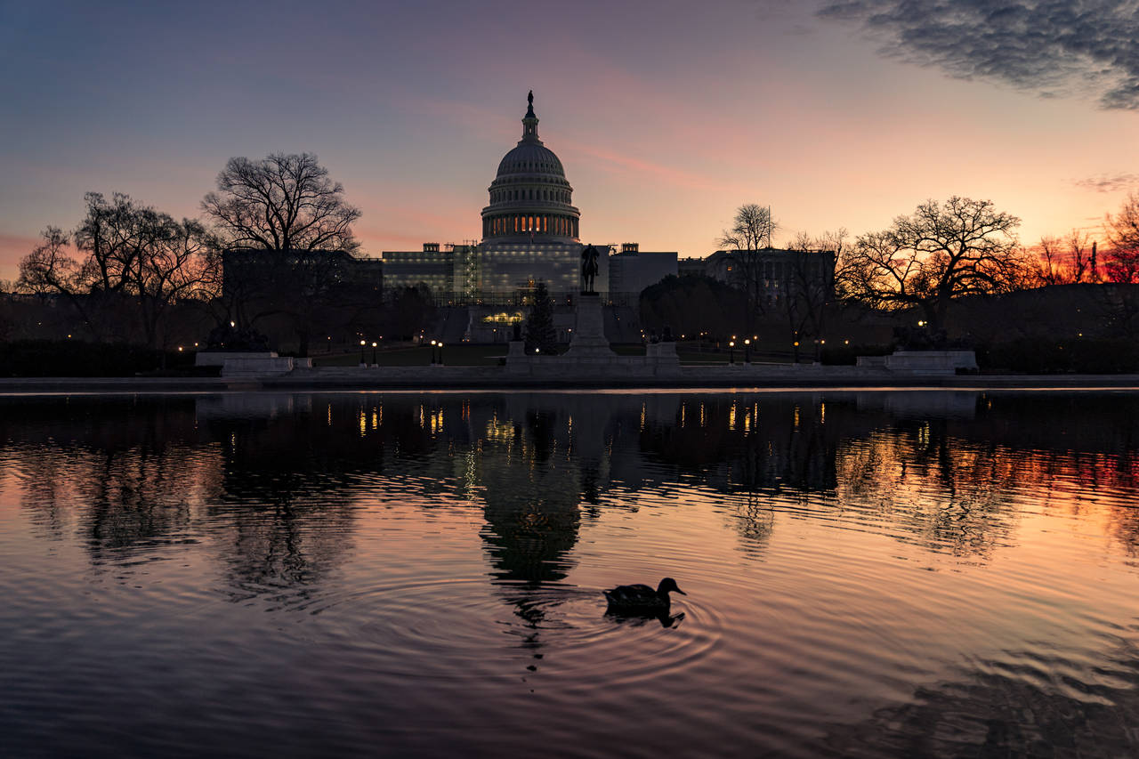 FILE - The sun rises behind the Capitol in Washington, early Wednesday, Dec. 14, 2022. Congressiona...