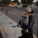 
              A friend of Monica Citlalli Diaz carries her photo on the sidelines of her funeral at a cemetery in Ecatepec, State of Mexico, Mexico, Friday, Nov. 11, 2022. The 30-year-old English teacher became the ninth apparent femicide during an 11-day spate of killings in and around Mexico City from late October to early November. (AP Photo/Eduardo Verdugo)
            