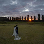 
              Chilean newlyweds Daniela Figueroa and Ricardo Torres, from Puerto Montt, Chile, look at moais statues at sunrise as they get cell phone photos taken by their tour guide on Ahu Tongariki, Rapa Nui, or Easter Island, Chile, Tuesday, Nov. 22, 2022. The couple spent their honeymoon on the island after COVID-19 restrictions did not allow them to hold the actual ceremony here earlier in the year. (AP Photo/Esteban Felix)
            
