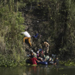 
              Venezuelan migrants climb onto U.S territory after crossing a river from Matamoros, Mexico, Thursday, Dec. 22, 2022. (AP Photo/Fernando Llano)
            