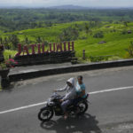 
              Motorists ride past rice fields fed by a traditional terrace irrigation system called a "subak" in Jatiluwih in Tabanan, Bali, Indonesia, Monday, April 18, 2022. Bali faces a looming water crisis from tourism development, population growth and water mismanagement, experts and environmental groups warn. While water shortages are already affecting the UNESCO site, wells, food production and Balinese culture, experts project these issues will worsen if existing policies are not equally enforced across the entire island. (AP Photo/Tatan Syuflana)
            