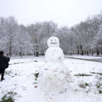 
              A woman photographs a snowman in Green Park in London, Monday, Dec. 12, 2022. Snow and ice have swept across parts of the UK, with cold wintry conditions set to continue for days. (AP Photo/Kirsty Wigglesworth)
            