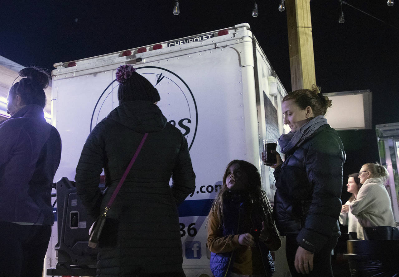 Elowyn Hoelscher, 7, stands in line at a food truck with her mother, Erika Hoelscher, at Red's Corn...