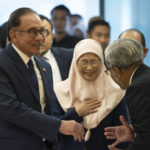 
              Malaysia's Prime Minister Anwar Ibrahim, left, and his wife Wan Azizah Ismail, center, are greeted by parliament staff as they arrive at Parliament House in Kuala Lumpur, Malaysia, Monday, Dec. 19, 2022. (AP Photo/Vincent Than, Pool)
            