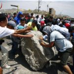 
              Supporters of ousted Peruvian President Pedro Castillo work together to roll a boulder onto the Pan-American North Highway during a protest against his detention, in Chao, Peru, Thursday, Dec. 15, 2022. Peru's new government declared a 30-day national emergency on Wednesday amid violent protests following Castillo's ouster, suspending the rights of "personal security and freedom" across the Andean nation. (AP Photo/Hugo Curotto)
            