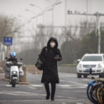 
              A woman wearing a face mask walks on a street in Beijing, Monday, Dec. 12, 2022, as capital city is hit by sandstorm. China will drop a travel tracing requirement as part of an uncertain exit from its strict "zero-COVID" policies that have elicited widespread dissatisfaction. (AP Photo/Andy Wong)
            
