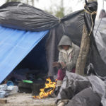 
              A Venezuelan migrant warms her hands over a campfire outside her makeshift tent refusing to be relocated to a refugee shelter, in Matamoros, Mexico, Friday, Dec. 23, 2022. Migrants are waiting along the U.S.-Mexico border on a pending U.S. Supreme Court decision on asylum restrictions. (AP Photo/Fernando Llano)
            