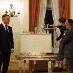 
              Poland's President Andrzej Duda, left, the country's chief rabbi, Michael Schudrich, right, and 8-year-old Hannah Ellis, daughter of a rabbi, together light a menorah during a Hanukkah ceremony at the presidential palace in Warsaw, Poland, Monday, Dec. 19, 2022. Poland's president led a Hanukkah ceremony on Monday where he paid tribute to Jewish communities in Poland and worldwide for the help they have extended to Ukrainian refugees this year. (AP Photo/Michal Dyjuk)
            