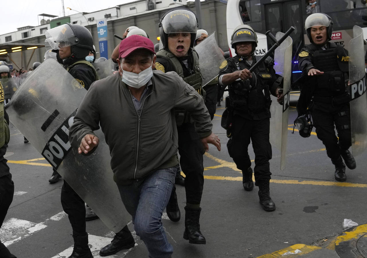 A riot police grabs hold of a supporter of former President Pedro Castillo outside the police stati...