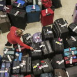 
              Airport staff looks at a tag on a pile of lost suitcases near the baggage carousel at Midway Airport, Tuesday, Dec. 27, 2022, after Southwest Airlines flights were cancelled and delayed during a winter storm.  Problems at Southwest Airlines appeared to snowball after the worst of the storm passed. It cancelled more than 70% of its flights Monday, more than 60% on Tuesday, and warned that it would operate just over a third of its usual schedule in the days ahead to allow crews to get back to where they needed to be. (Pat Nabong /Chicago Sun-Times via AP)
            