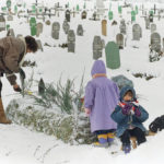 
              FILE - Fatima Ramic, with her daughter Alma, right and niece Elma, back to camera, tends to the grave of her 8-year-old son, Alija, who died the previous year from medical complications in Sarajevo's Kosevo hospital on Jan. 5, 1995. The mother says her son is a victim of the war due to inadequate facilities and medicines available to the sick and injured of the Bosnian capital. (AP Photo/Rikard Larma, File)
            