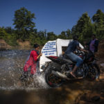 
              Lata Netam, a health worker, unsuccessfully tries to push a motorbike ambulance, up a steep riverbank through Abhujmarh, or "the unknown hills," to reach a pregnant woman in Kodoli, a remote village near Orchha in central India's Chhattisgarh state, Nov. 15, 2022. These ambulances, first deployed in 2014, reach inaccessible villages to bring pregnant women to an early referral center, a building close to the hospital where expectant mothers can stay under observation, routinely visit doctors if needed until they give birth. Since then the number of babies born in hospitals has doubled to a yearly average of about 162 births each year, from just 76 in 2014. The state has one of the highest rates of pregnancy-related deaths for mothers in India, about 1.5 times the national average, with 137 pregnancy related deaths for mothers per 100,000 births. (AP Photo/Altaf Qadri)
            