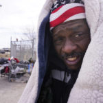 
              Kevin Hall uses a blanket to keep warm from freezing temperatures while standing on the street in Fort Worth, Texas, Friday, Dec. 23, 2022. (AP Photo/LM Otero)
            