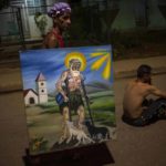 
              A follower of Saint Lazaro carries a painting depicting the saint, during a pilgrimage to the San Lazaro shrine in El Rincon, an area of Santiago de las Vegas, Cuba, Friday, Dec. 16, 2022. The Catholic saint is also known as the Afro-Cuban Yoruba deity Babalu Aye, protector of the sick, an example of Cuba's religions syncretism, whose feast day is celebrated on Dec. 17. (AP Photo/Ramon Espinosa)
            