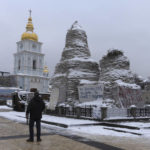 
              A man looks at St. Michael Cathedral standing near a monument to Princess Olga covered with sand bags to protect it from the Russian shelling, with placards displayed near the monument calling to support Ukraine, in central Kyiv, Ukraine, Monday, Dec. 12, 2022. Ukraine has been fighting with the Russian invaders since Feb. 24 for over nine months. (AP Photo/Efrem Lukatsky)
            