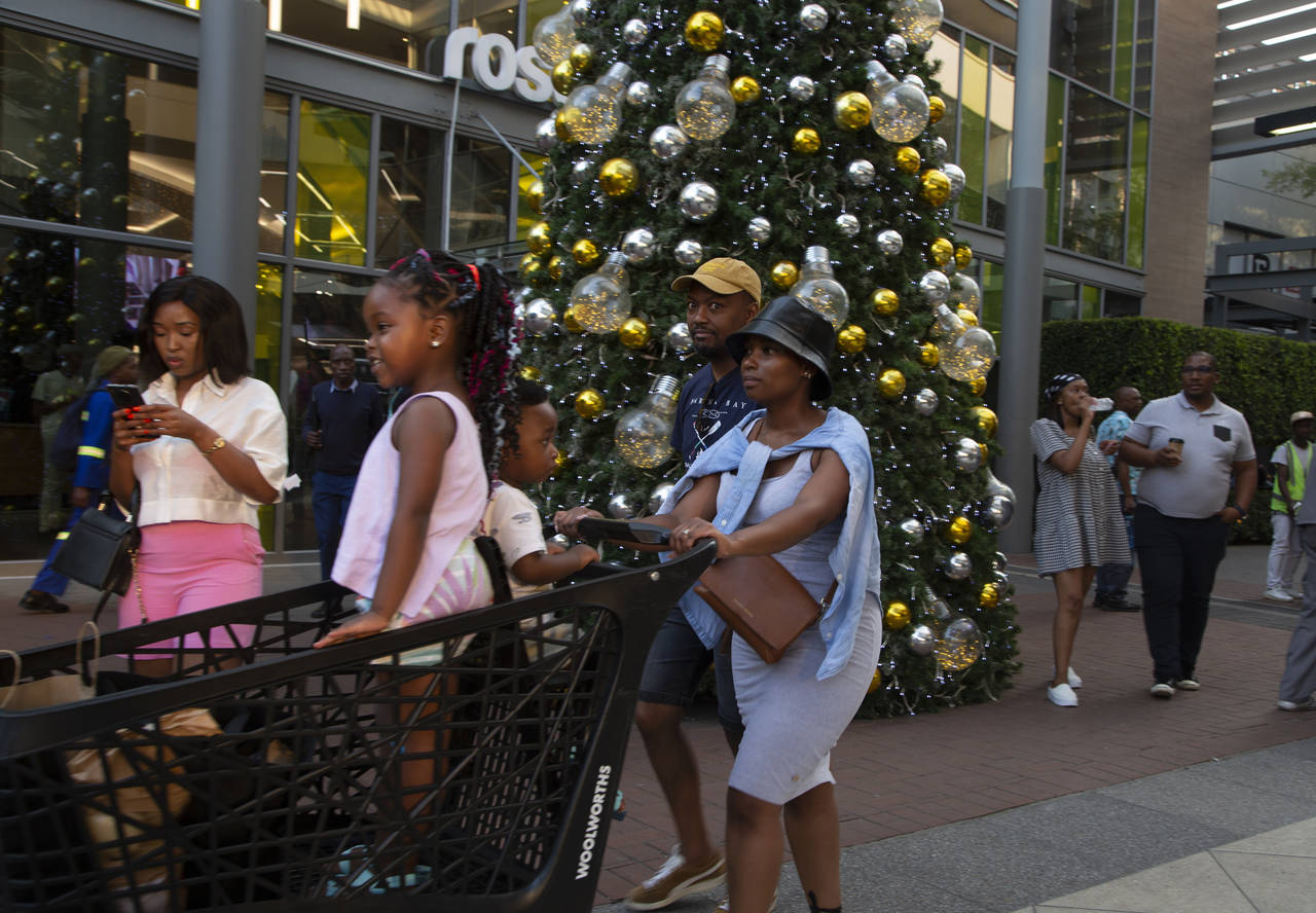 Shoppers pass a Christmas tree at the entrance to the Rosebank Shopping Mall in Johannesburg Saturd...