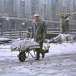 
              A man pushes his wheelbarrow loaded with supplies across an intersection frequently fired upon by sniper near the Miljacka River in Sarajevo on Tuesday, Jan. 26, 1993, as cold and snow returned to the besieged Bosnian capital. In the background is a destroyed bus station. (AP Photo/Hansi Krauss)
            