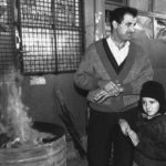 
              FILE - A father and his son stand in front of a destroyed store warming themselves up on an open fire in downtown Sarajevo, Wednesday, Oct. 14, 1992. For nearly four years, Sarajevo’s roughly 350,000 residents were trapped and faced daily shelling and sniper attacks. Cut off from regular access to electricity, heat and water, they survived on limited humanitarian aid from the United Nations while drinking from wells and foraging for food. (AP Photo/Hansi Krauss, File)
            