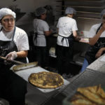 
              Jinane Hayek, left, who lost her job as a branch manager at one of the largest banks in Lebanon two years ago, prepares local pastries called "Manakish" at her own bakery in Bekfaya town, in the Mount Lebanon governorate, Lebanon, Friday, Sept. 23, 2022. Hayek worked in Lebanon's banking sector for nearly three decades but lost her job after the country's economic meltdown began.  (AP Photo/Bilal Hussein)
            