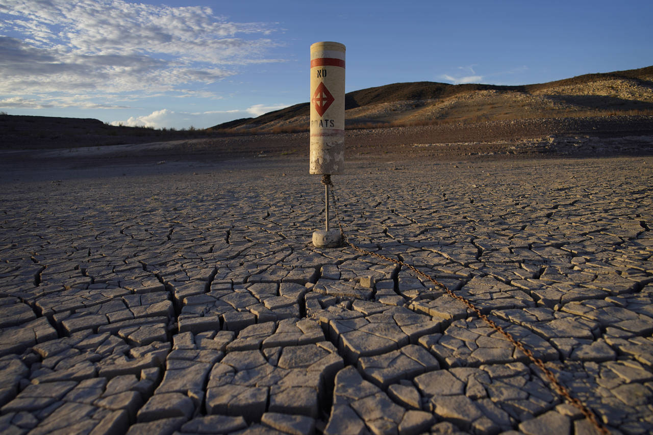 FILE - A buoy sits high and dry on cracked earth previously under the waters of Lake Mead at the La...