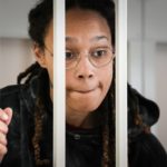 
              FILE - WNBA star and two-time Olympic gold medalist Brittney Griner speaks to her lawyers standing in a cage at a court room prior to a hearing, in Khimki just outside Moscow, Russia, on July 26, 2022.  Russia has freed WNBA star Brittney Griner on Thursday in a dramatic high-level prisoner exchange, with the U.S. releasing notorious Russian arms dealer Viktor Bout. (AP Photo/Alexander Zemlianichenko, Pool, File)
            