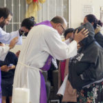 
              The Rev. Brian Strassburger, left, and the Rev. Flavio Bravo, right, bless migrants during Mass at the Casa del Migrant shelter in Reynosa, Mexico, on Dec. 15, 2022. Both hope and tension have been rising here and the few other shelters in this border city where thousands of migrants await news of U.S. border policy changes possibly less than a week away. (AP Photo/Giovanna Dell'Orto)
            