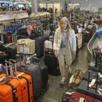 
              Chicago traveler Shana Schifer walks through unclaimed bags at Southwest Airlines baggage claim at Salt Lake City International Airport Thursday, Dec. 29, 2022, in Salt Lake City. Southwest Airlines said it expects to return to normal operations Friday after slashing about two-thirds of its schedule in recent days, including canceling another 2,350 flights Thursday. (AP Photo/Rick Bowmer)
            