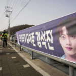 
              South Korean police officers pass by a banner showing an image of K-pop band BTS's member Jin near an army training center in Yeoncheon, South Korea, Tuesday, Dec. 13, 2022. Jin is set to enter a frontline South Korean booth camp on Tuesday to start his 18 months of mandatory military service, as fans are gathering near the base to say goodbye to their star. (AP Photo/Ahn Young-joon)
            