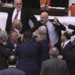 
              Zafer Isik, a lawmaker from president Recep Tayyip Erdogan's ruling party, rear center, punches Huseyin Ors, a lawmaker from the opposition Good Party, third left, in the face at the parliament, in Ankara, Turkey, Tuesday, Dec. 6, 2022. Ors was hospitalized on Tuesday following a brawl that broke out in Turkey's parliament during a tense debate over next year's budget. (AP Photo)
            