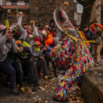 
              People throw turnips at the Jarramplas as he makes his way through the streets beating his drum during the Jarramplas festival in the tiny southwestern Spanish town of Piornal, Spain, Friday, Jan. 20, 2023. The Jarramplas festival features a man in multicolored garb and pointy wooden headgear to shield himself from turnips. A crowd of men in the street pelt the man with the vegetables from close range at the fiesta held annually at Piornal, 200 kilometers west of Madrid, over two days. (AP Photo/Manu Fernandez)
            
