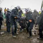 
              Police officers carry a demonstrator to clear a road at the village Luetzerath near Erkelenz, Germany, Tuesday, Jan. 10, 2023. The village of Luetzerath is occupied by climate activists fighting against the demolishing of the village to expand the Garzweiler lignite coal mine near the Dutch border. (AP Photo/Michael Probst)
            