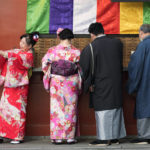 
              A group of tourists from Singapore in Japan's traditional kimono attire buy fortune paper as one of them takes a selfie at Sensoji Buddhist temple in Tokyo, Friday, Jan. 13, 2023. (AP Photo/Hiro Komae)
            