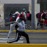 
              An anti-government protester hurls stones at the police during clashed in Lima, Peru, Tuesday, Jan. 24, 2023. Protesters are seeking the resignation of President Dina Boluarte, the release from prison of ousted President Pedro Castillo, immediate elections and justice for demonstrators killed in clashes with police. (AP Photo/Martin Mejia)
            