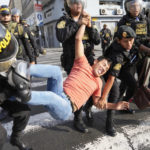 
              An anti-government protesters who traveled to the capital from across the country to march against Peruvian President Dina Boluarte, is detained by the police during clashes in Lima, Peru, Thursday, Jan. 19, 2023. Protesters are seeking immediate elections, Boluarte's resignation, the release of ousted President Pedro Castillo and justice for up to 48 protesters killed in clashes with police. (AP Photo/Martin Mejia)
            