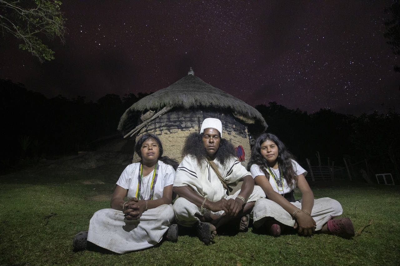 Arhuaco Indigenous siblings, twins Irene, left, Alba, 16, and Sebastian, 30, center, sit in front o...