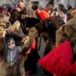 
              A little boy dances during a parade showcasing regional winter traditions in Comanesti, northeastern Romania, Friday, Dec. 30, 2022. Every year on Dec. 30 bear hundreds of people dressed as bears, from toddlers to adults, fill the main street growling as they dance or jokingly simulating aggressive moves towards the many onlookers. (AP Photo/Vadim Ghirda)
            