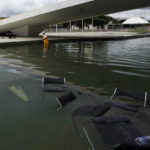 
              Furniture that was thrown from the ramp of Planalto Palace lay in the reflection pool where a worker collects them, the day after the office of the president was stormed by supporters of Brazil's former President Jair Bolsonaro in Brasilia, Brazil, Monday, Jan. 9, 2023. The protesters also stormed Congress and the Supreme Court. (AP Photo/Eraldo Peres)
            