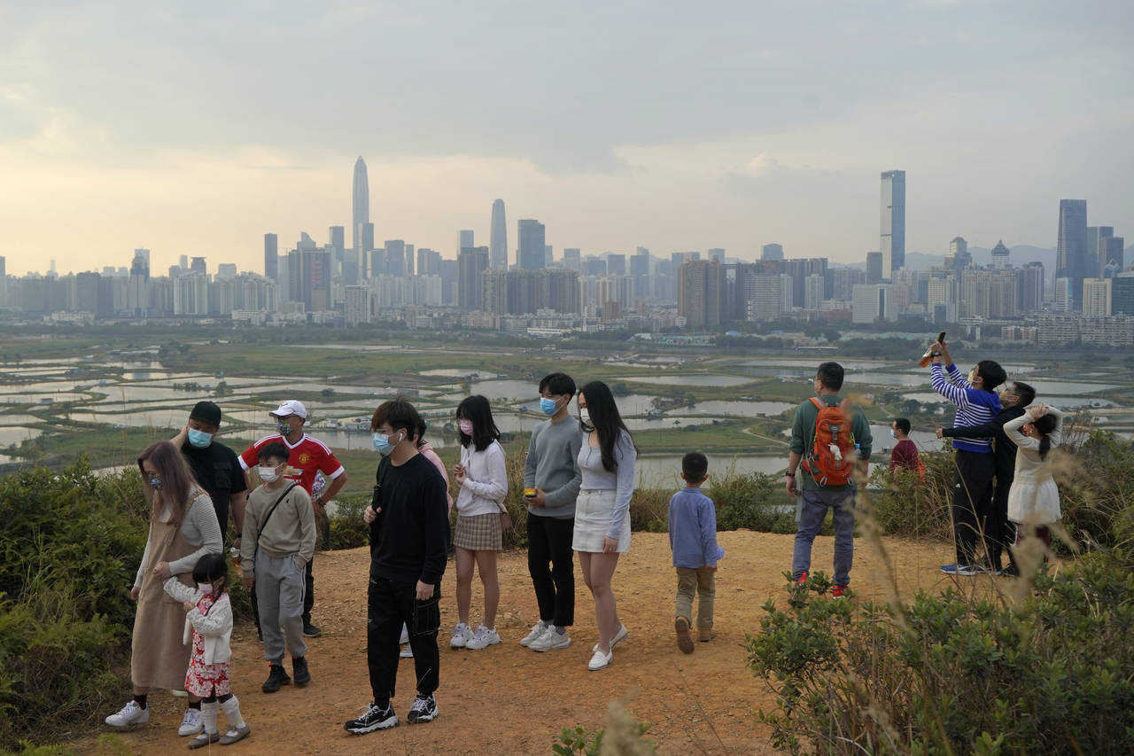 FILE - People visit the border of Hong Kong, with the skyline of China's Shenzhen in the background...