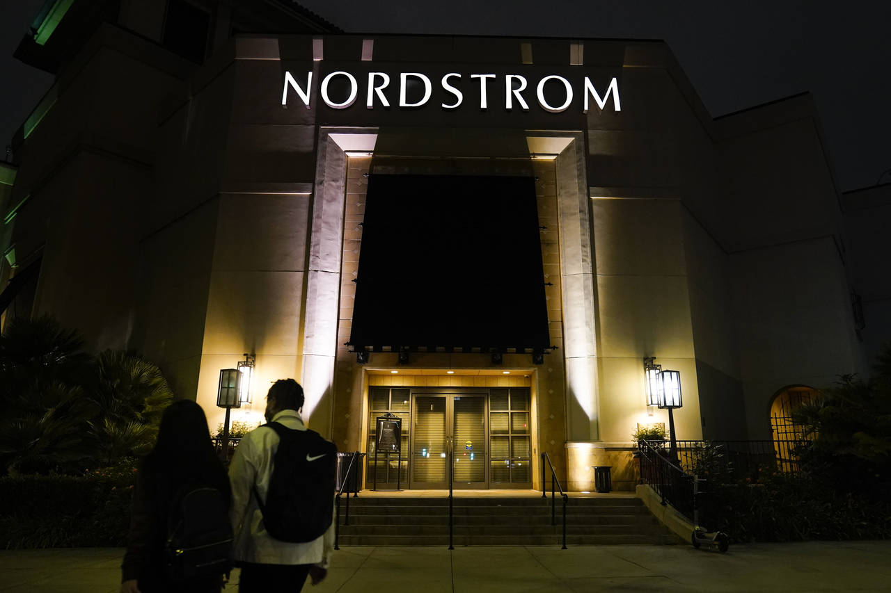 FILE - Two pedestrians walk near a closed street entrance to a Nordstrom department store at the Gr...