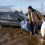 
              Jesus Torres carries belongings from his flooded Merced, Calif., home on Tuesday, Jan. 10, 2023. (AP Photo/Noah Berger)
            