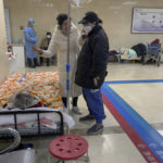 
              Women chat as elderly patients on stretchers receive treatment in the hallway of an emergency ward in Beijing, Thursday, Jan. 19, 2023. China on Thursday accused "some Western media" of bias, smears and political manipulation in their coverage of China's abrupt ending of its strict "zero-COVID" policy, as it issued a vigorous defense of actions taken to prepare for the change of strategy. (AP Photo/Andy Wong)
            