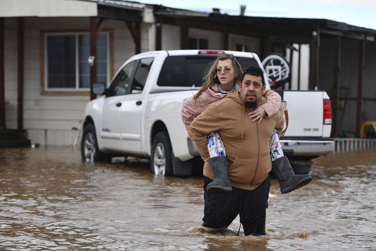 Ryan Orosco, of Brentwood, carries his wife Amanda Orosco, from their flooded home on Bixler Road i...