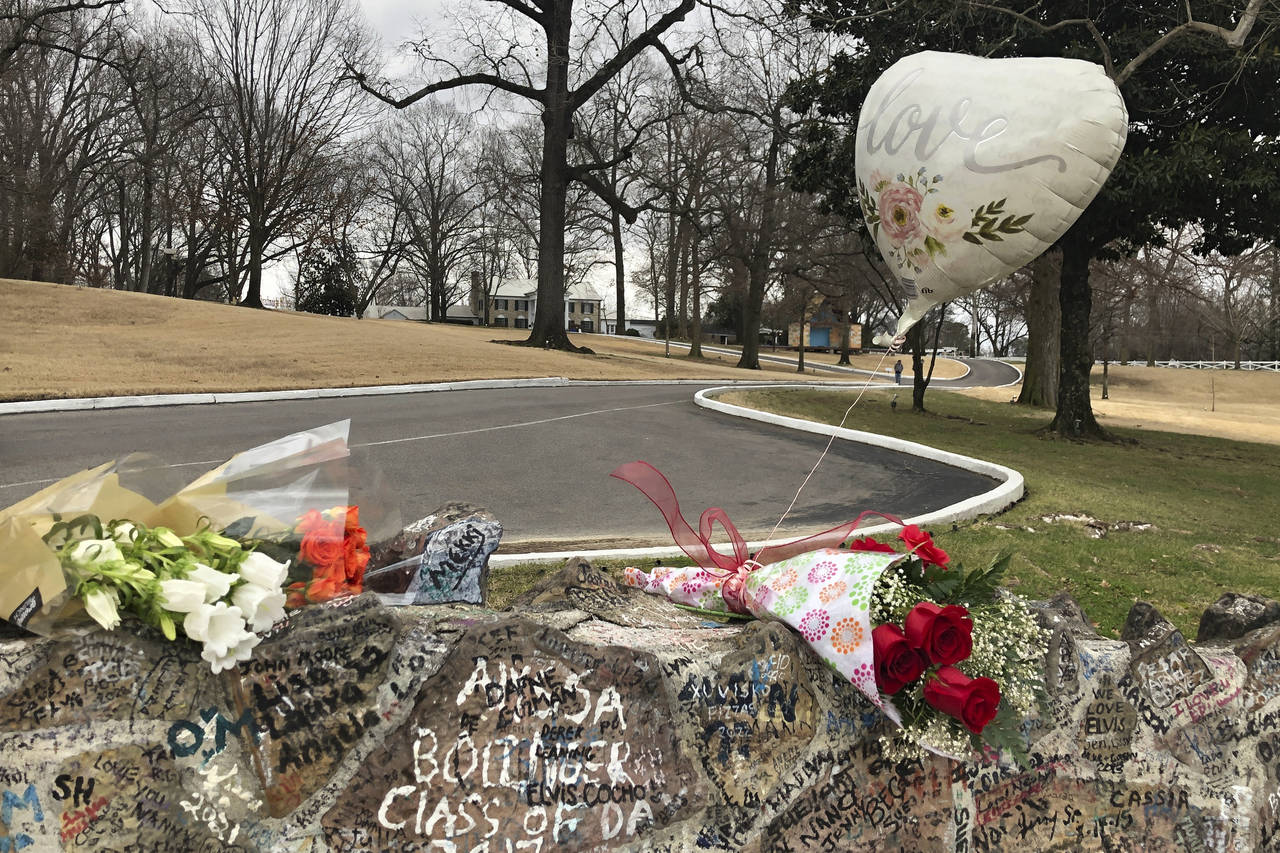 Bouquets of flowers and a balloon line the stone wall at Graceland on Friday, Jan. 13, 2023, in Mem...