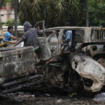 
              People help themselves to parts of charred vehicles sitting parked outside the state prosecutor office that were set on fire last week during a protest against the imprisonment of the opposition leader and governor of Santa Cruz Luis Fernando Camacho, in Santa Cruz, Bolivia, Tuesday, Jan. 3, 2023. Prosecutors in Bolivia on Dec. 29, 2022, called for Camacho to be remanded in custody for six months in prison while he faces terrorism charges. (AP Photo/Juan Karita)
            