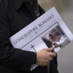 
              A man holds a copy of the Vatican newspaper as he waits to view the body of Pope Emeritus Benedict XVI as it lies in state in St. Peter's Basilica at the Vatican, Tuesday, Jan. 3, 2023. The Vatican announced that Pope Benedict died on Dec. 31, 2022, aged 95, and that his funeral will be held on Thursday, Jan. 5, 2023. (AP Photo/Ben Curtis)
            