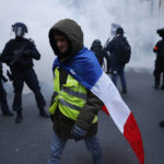 
              A demonstrator walks past riot police officers during a demonstration against pension changes, Thursday, Jan. 19, 2023 in Paris. Workers in many French cities took to the streets Thursday to reject proposed pension changes that would push back the retirement age, amid a day of nationwide strikes and protests seen as a major test for Emmanuel Macron and his presidency. (AP Photo/Lewis Joly)
            