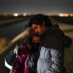 
              Cuban migrant Mario Perez holds his wife as they wait to be processed to seek asylum after crossing the border into the United States, Friday, Jan. 6, 2023, near Yuma, Ariz. President Joe Biden says the U.S. will immediately begin turning away Cubans, Haitians and Nicaraguans who cross the border from Mexico illegally. It's his boldest move yet to confront spiraling arrivals of migrants since he took office two years ago. (AP Photo/Gregory Bull)
            