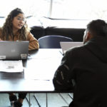 
              Miriam Jimenez, left, intake coordinator for Denver Human Services, speaks with a migrant at a makeshift shelter in Denver, Friday, Jan. 6, 2023. Over the past month, nearly 4,000 immigrants, almost all Venezuelans, have arrived unannounced in the frigid city, with nowhere to stay and sometimes wearing T-shirts and flip-flops. In response, Denver converted three recreation centers into emergency shelters for migrants and paid for families with children to stay at hotels, allocating $3 million to deal with the influx. (AP Photo/Thomas Peipert)
            
