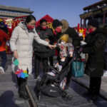 
              Chinese families visit to Qianmen pedestrian shopping street on the first day of the Lunar New Year holiday in Beijing, Sunday, Jan. 22, 2023. People across China rang in the Lunar New Year on Sunday with large family gatherings and crowds visiting temples after the government lifted its strict "zero-COVID" policy, marking the biggest festive celebration since the pandemic began three years ago. (AP Photo/Andy Wong)
            