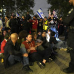 Activists lock arms in Tel Aviv, Israel, to protest against Prime Minister Benjamin Netanyahu's far-right government, Saturday, Jan. 7, 2023. Thousands of Israelis protested plans by Netanyahu's government that opponents say threaten democracy and freedoms. (AP Photo/ Tsafrir Abayov)